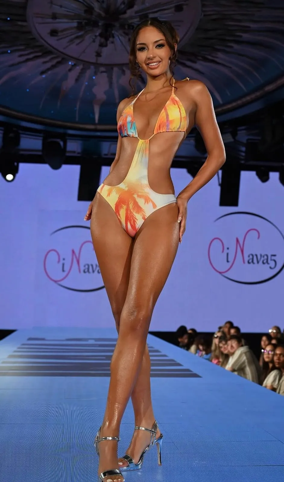 A model in an orange and yellow one-piece swimsuit on the runway