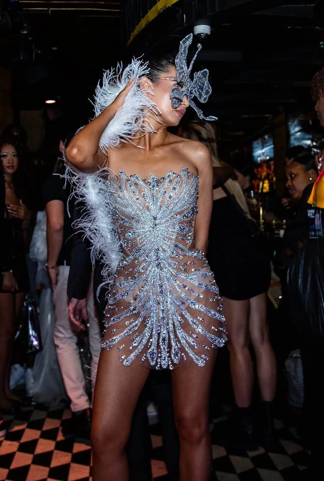 A model in a crystal and feather corset dress backstage
