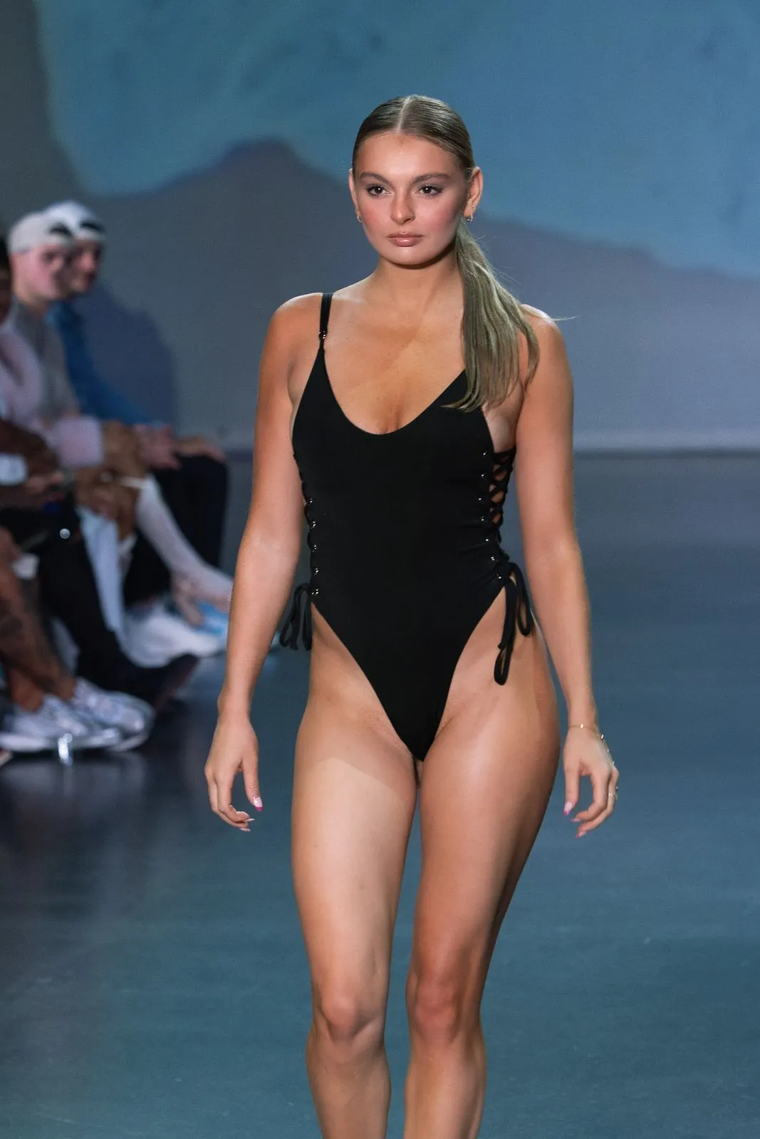 A model in a black one-piece swimsuit on the runway